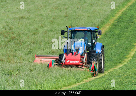 Mähen einer Wiese mit einem New Holland T7 Traktor mit Kvernland Front- und Seitenairbags Mähaufbereiter auf. Cumbria, UK. Stockfoto