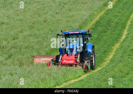 Mähen einer Wiese mit einem New Holland T7 Traktor mit Kvernland Front- und Seitenairbags Mähaufbereiter auf. Cumbria, UK. Stockfoto