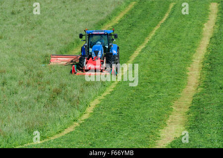 Mähen einer Wiese mit einem New Holland T7 Traktor mit Kvernland Front- und Seitenairbags Mähaufbereiter auf. Cumbria, UK. Stockfoto