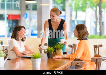 Kellnerin serviert zwei glückliche Frauen in einem restaurant Stockfoto