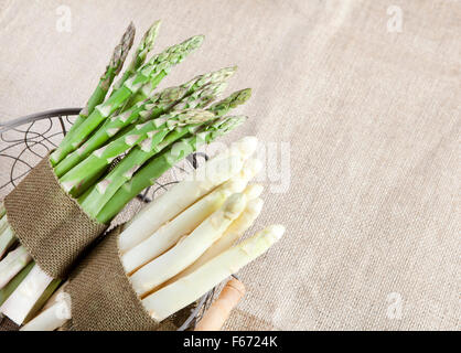 frischer grüner und weißer Spargel in einen Korb mit einem Tuch Band gebündelt Stockfoto