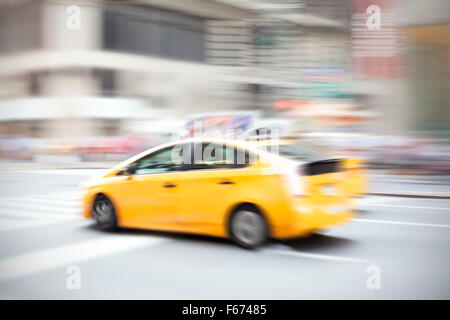 Bewegung verwischt gelbes Taxi auf einer Stadtstraße. Stockfoto