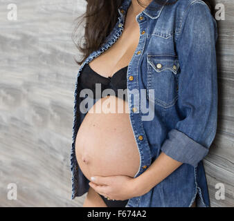 Die süßen Erwartung einer Schwangeren mit einem Jeanshemd. Stockfoto