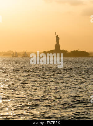 Freiheitsstatue vor Sonnenuntergang im dunstigen New Yorker Hafen Stockfoto