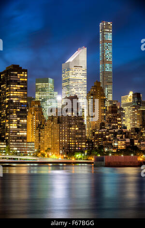 Beleuchtete Midtown Manhattan Wolkenkratzer und Lichter der Stadt spiegeln sich im East River in der Dämmerung. Skyline von New York City.