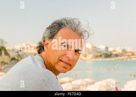 Lächelnd und gebräunte Mann mittleren Alters kaukasischen erholsamen Urlaub vor dem atemberaubenden Panorama von einem italienischen Küstenstadt Stockfoto