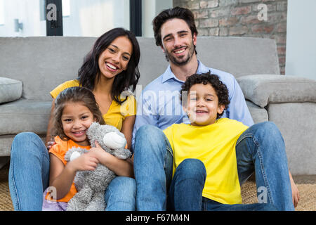 Lächelnd Familie sitzen auf Teppich im Wohnzimmer Stockfoto