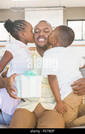 Glücklicher Vater wird von seinen beiden Kindern geküsst. Stockfoto