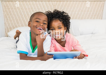 Glücklich Geschwister mit Tablet auf Bett Stockfoto