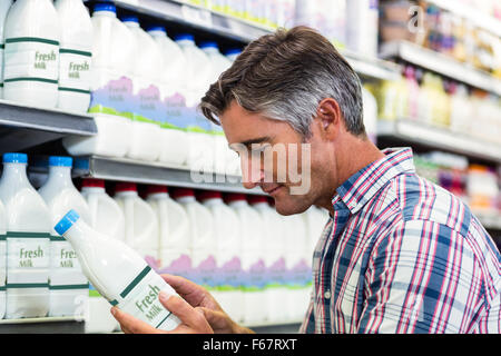 Gut aussehender Mann in den Supermarkt Milchflasche betrachten Stockfoto