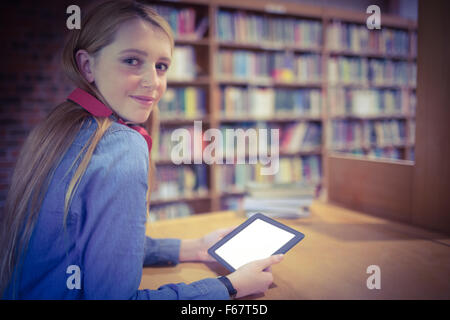 Hübsche Studentin mit Kopfhörern mit Tablet in Bibliothek Stockfoto