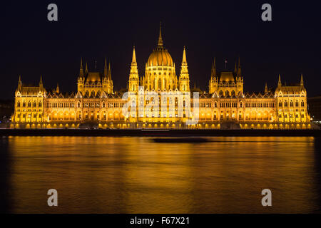 Ein Blick auf das ungarische Parlamentsgebäude an der Donau in der Nacht mit dem Bau beleuchtet und Reflexionen in der wate Stockfoto