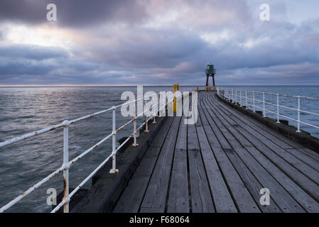 Blick entlang Whitbys West Pier in der Dämmerung - Blau-Grau-Töne von Holzbrettern, Meer und Himmel, schaffen eine ruhige, stimmungsvolle, ruhige Szene. Yorkshire, GB, UK. Stockfoto