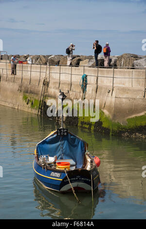 Menschen nehmen Sie Fotos auf Wellenbrecher & kleine Angelboot/Fischerboot (entgeisterung) vor Anker im Meer Hafen - sonnigen Sommertag mit blauem Himmel am Staithes, North Yorkshire, UK. Stockfoto