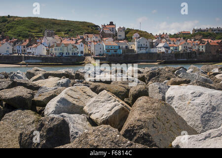 Sonnige Sommer Blick auf malerische Dorf von Staithes, North Yorkshire, UK, gesehen von hinten Küstenschutzes (Rüstung Felsbarriere) zum Schutz des Hafens. Stockfoto