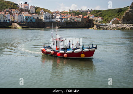 Sonnigen Sommertag & vier Männer auf einem Angelausflug Boot Meer verlassen den Hafen & Küsten, malerische Dorf von Staithes, North Yorkshire, England, UK. Stockfoto