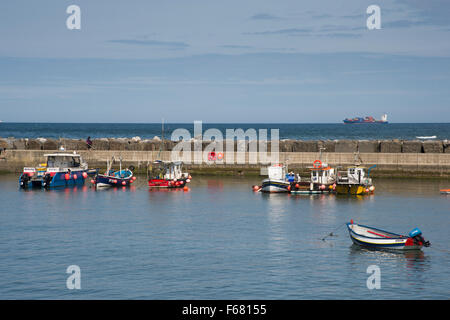 Angeln, Boote und Cobles vertäut im Tierheim auf den malerischen Hafen, Staithes, North Yorkshire, Großbritannien an einem ruhigen, sonnigen Sommertag mit blauem Himmel & Meer. Stockfoto