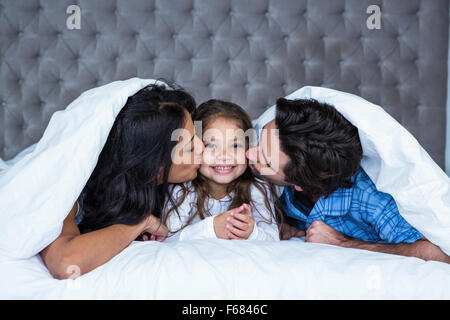 Glückliche Eltern küssen Tochter Stockfoto