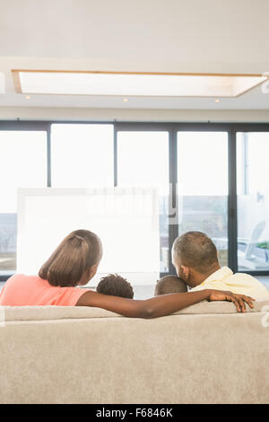 Schulter-Blick über lässige Familie vor dem Fernseher Stockfoto