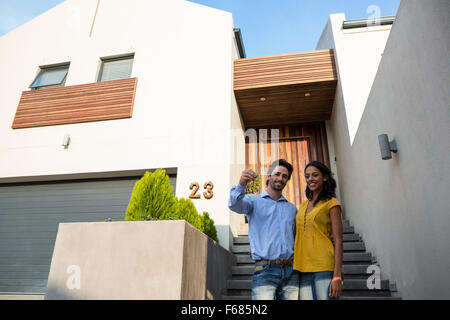 Glückliches Paar vor neuen Hausschlüssel anzeigen Stockfoto