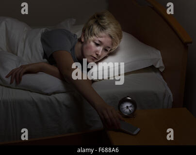 Teenager-Mädchen für ihr Handy, über Nacht stehen, während im Bett zu erreichen. Teen mit Technologie spät in der Nacht statt zu schlafen. Stockfoto