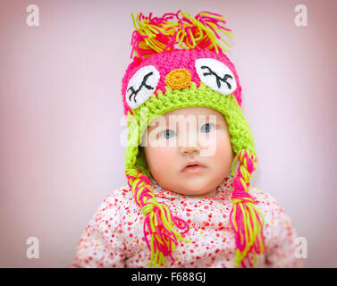 Porträt von schönen Mädchen Baby tragen stilvolle bunt gestrickte Mütze über rosa Hintergrund, Winter Kindermode Stockfoto