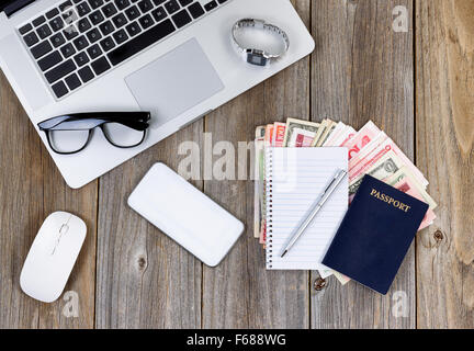 Desktop mit Technologie und Papier-Währung für Reiseplan. Hoher seitlicher Blick mit vertikalen rustikalen Holzbretter. Stockfoto