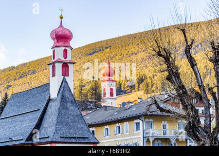 Der rote Turm und die Dächer von Menschen freundlich Alpenstadt im Hintergrund von grünen Bergen in den italienischen Alpen Stockfoto