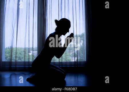 Setzen Sie sich im Gebet Silhouette Frau Stockfoto