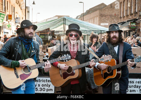 Drei Straßenmusiker spielt Gitarre in Broadway Market, Hackney, London, England, UK Stockfoto