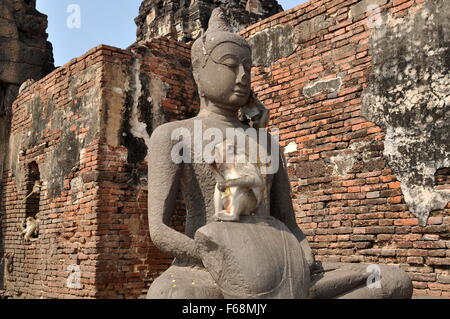 Lopburi, Thailand: Affen Sie Essen Mais beim Sitzen auf eine Buddha-Statue in den Ruinen der historischen Khmer Wat Phra Prang Sam Yot Stockfoto