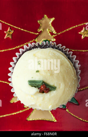 Christmas Pudding Red Velvet Muffin auf Weihnachtsteller mit gold Baum und Sterne Stockfoto