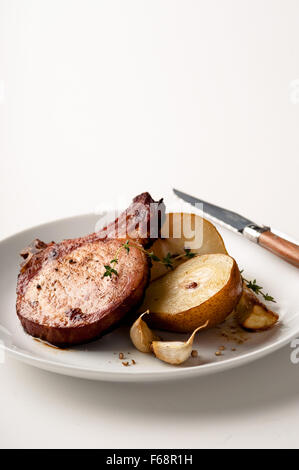 Gebratenes Schweinekotelett und Birnen mit Knoblauch, Pfeffer & Kräuter würzen. Stockfoto