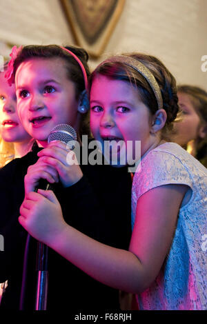 Vertikale Porträt der jungen Mädchen singen Karaoke auf einer Geburtstagsfeier. Stockfoto