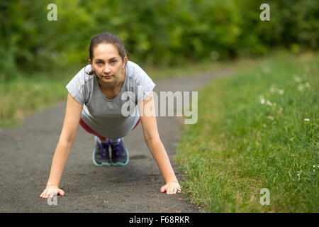 Junge Mädchen tun Push Ups aus dem Boden im Training im Freien. Stockfoto