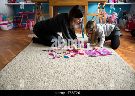 Horizontale Porträt von einem kleinen Mädchen und ihre Mutter, die mit traditionellen Plastikziegelsteine im Spielzimmer spielen. Stockfoto