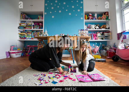 Horizontale Porträt von einem kleinen Mädchen und ihre Mutter, die mit traditionellen Plastikziegelsteine im Spielzimmer spielen. Stockfoto