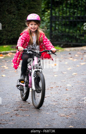 Vertikale Porträt eines jungen Mädchens mit ihrem Fahrrad auf der Straße. Stockfoto