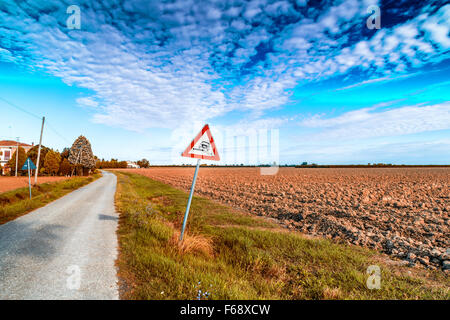 Gefährliche Schulter Ruropean Schild Kiesweg in italienischen Landschaft am Himmelshintergrund Stockfoto