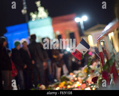 Berlin, Deutschland. 14. November 2015. Eine französische Flagge und eine rote Rose hängen von einer Barriere vor der französischen Botschaft am Brandenburger Tor in Berlin, Deutschland, 14. November 2015. Das Brandenburger Tor ist in den französischen Nationalfarben beleuchtet. Mindestens 120 Menschen starben in einer Reihe von Terroranschlägen in Paris. Foto: LUKAS SCHULZE/DPA/Alamy Live-Nachrichten Stockfoto