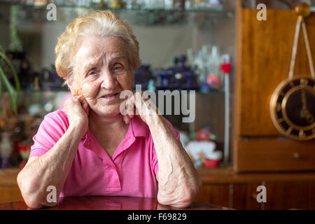 Eine ältere Frau saß am Tisch im Zimmer. Stockfoto