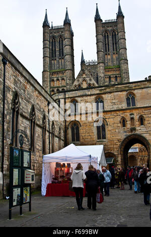 Lincoln, England, Chriskindlemarkt, Verkaufsstände und faire Besucher auf einer Straße unter den Mauern der Stadt und Türme der Kathedrale Stockfoto