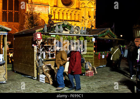 Lincoln, England, Chriskindlemarkt, eine Straßenszene unter den Burgmauern von fair Urlauber an einem Kranz und grünen Stand. Stockfoto