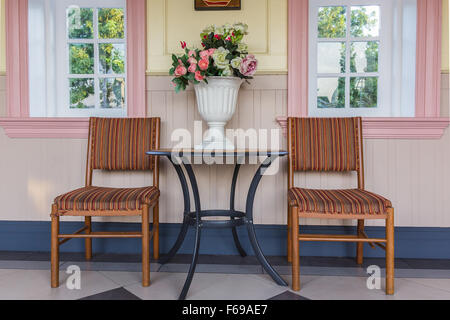 Zwei Stühle und Tisch mit Blumenstrauss in Vase auf einer Terrasse Stockfoto