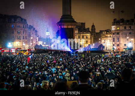 London, UK. 14. November 2015. Tausende versammeln sich am Trafalgar Square für ein Candle-Light-Mahnwache in Solidarität mit den Opfern von gestern Abend Terroristen Anschläge in Paris. Die National Portrait Gallery ist mit den Farben der französischen Tricolore Flagge beleuchtet. Stockfoto