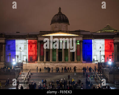 London, UK. 14. November 2015. Tausende versammeln sich am Trafalgar Square für ein Candle-Light-Mahnwache in Solidarität mit den Opfern von gestern Abend Terroristen Anschläge in Paris. Die National Portrait Gallery ist mit den Farben der französischen Tricolore Flagge beleuchtet. Stockfoto