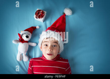 Fröhlicher Junge im Weihnachtsmann-Mütze mit ein weißer Bär auf blauem Hintergrund Stockfoto