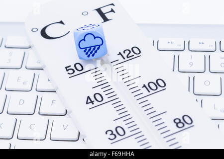 Bild zeigt einen Thermometer mit Würfel auf einer Tastatur Stockfoto