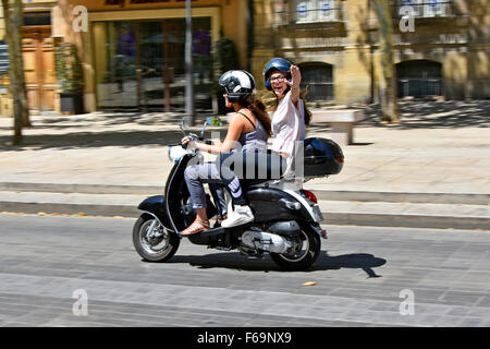 Aix en Provence Südfrankreich unbeschwerten Mädchen winken & Reiten Sozius auf Motorroller entlang des Boulevard Cours Mirabeau im heißen Juli Sommertag Stockfoto