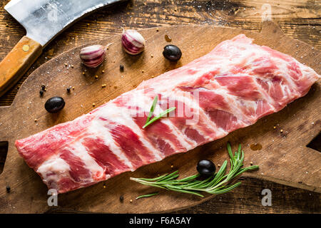 Schweinerippchen mit Gewürzen ungekocht auf Holzbrett. Rostige Stil, hoher Kontrast Stockfoto